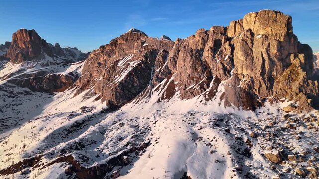 Drone approaching Ra Gusela sunlit summit with Averau and Nuvolau in background, Dolomites