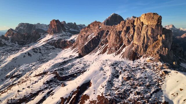 Close drone orbit of Ra Gusela golden rock face at sunset with Nuvolau behind, Dolomites