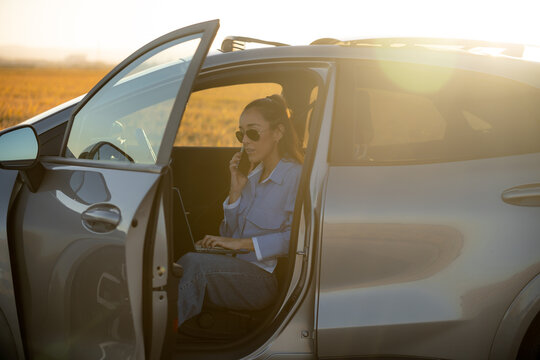 Female digital nomad working remotely from car at sunset