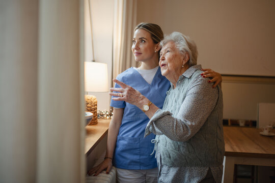 Caring healthcare worker visiting a senior patient at home, hugging her.