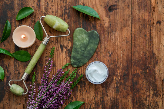 Spa skincare flat lay with jade roller, candle and flower
