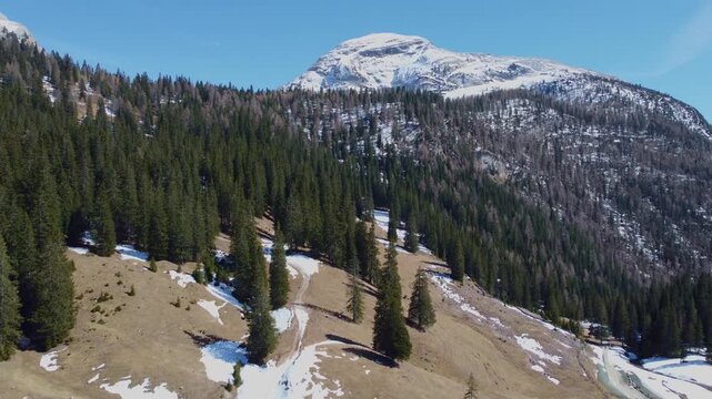 Drone tracking past forest slope toward Croda de r'Ancona and mountain hut, Sennes