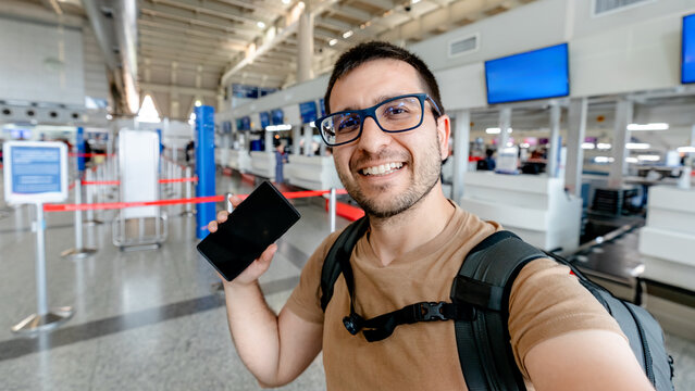 Smiling traveler with smartphone at airport check-in hall
