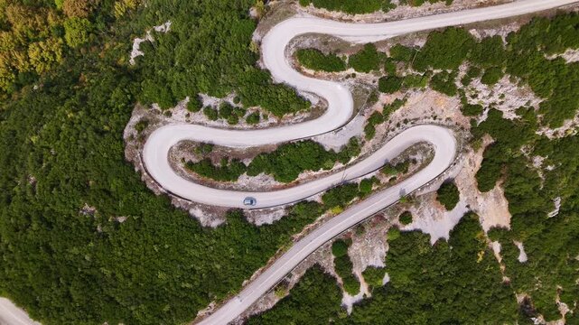 Hairpin mountain road zigzagging toward stone village in Pindus Mountains, Zagori, Greece