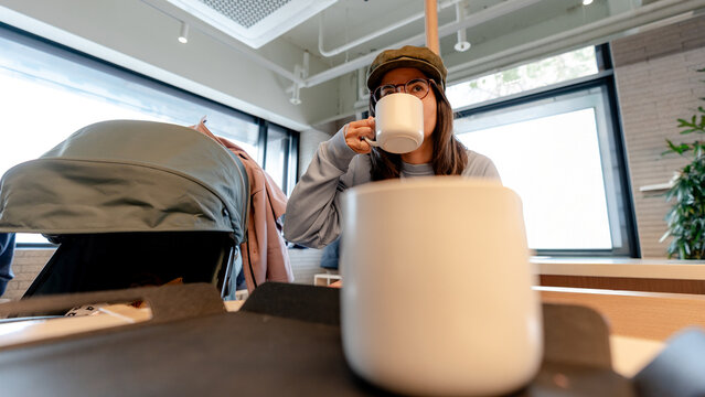 Mother with stroller enjoying coffee in a bright cafe