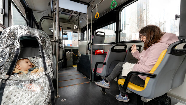 Mother waves to baby in stroller on city bus ride