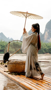 Hanfu girl with cormorant on bamboo raft in Xingping