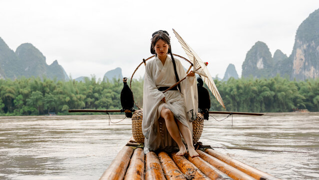 Hanfu girl on bamboo raft with cormorants in Xingping