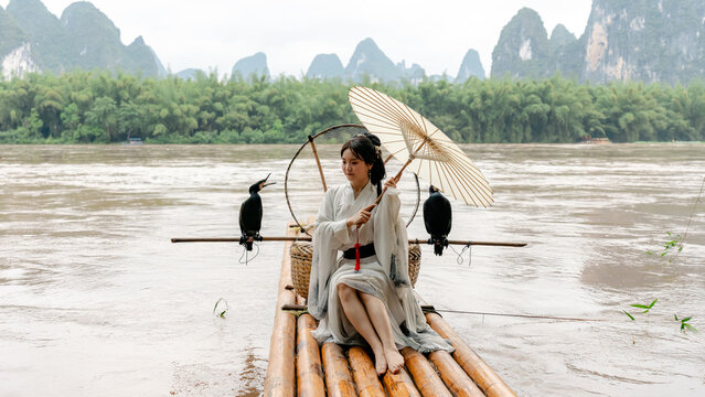 Hanfu girl on bamboo raft with cormorant in Xingping