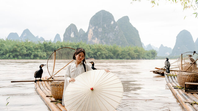 Hanfu girl with cormorant on bamboo raft in Xingping