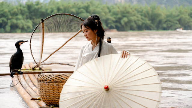 Hanfu girl with cormorant on bamboo raft in Xingping