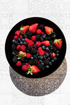 Bowl of fresh mixed berries on patterned tile background