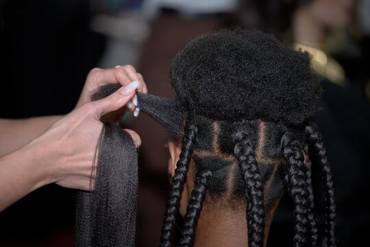 A trainer demonstrates the technique of curling African braids.