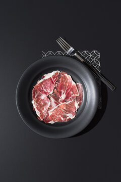Spanish acorn-cured ham slices on black plate