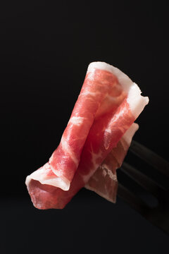Close-up of sliced Spanish Iberian cured ham on black
