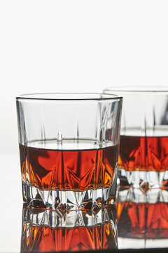 Crystal tumbler with bourbon whisky on reflective bar