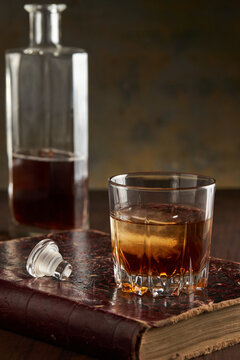 Still life of bourbon whisky in glass on vintage book