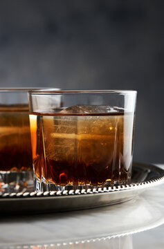 Close up of bourbon whisky in glass with ice on tray