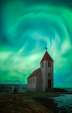Icelandic church under swirling northern lights at night