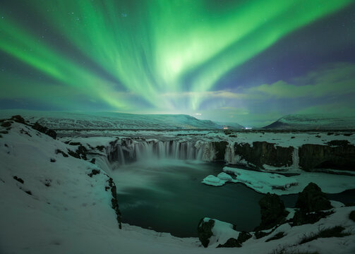 Winter aurora over icy waterfall canyon in Iceland