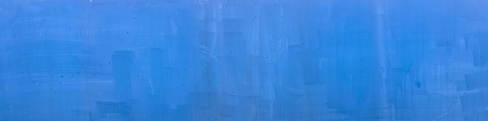Fototapeta premium The metal surface is painted with a blue roller and has scuffs, scratches, paint splashes. iron surface is covered with old, sun-bleached light blue paint paint texture background. Horizontal photo.