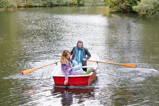 Romantic couple rowing a boat on calm lake in autumn