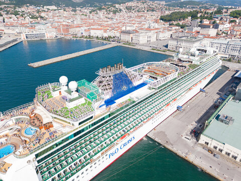 TRIESTE, ITALIA - 18 MAGGIO 2026: Veduta aerea della nave da crociera Ventura ormeggiata alla Stazione Marittima con lo sfondo del panorama cittadino