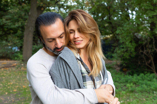 Affectionate couple hugging outdoors in park, family love