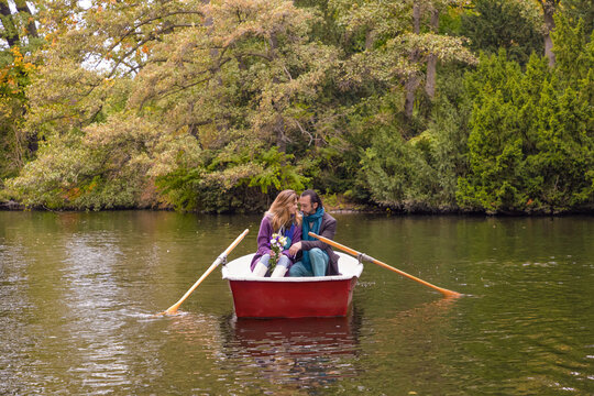 Romantic couple rowing a boat on a calm lake in autumn