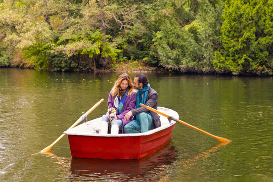 Romantic couple in rowboat on calm lake in autumn park