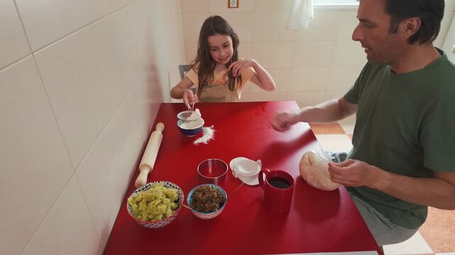 Father and Daughter Prepare Delicious Homemade Vareniki Together in the Kitchen, Sifting Flour and Handling Fresh Dough