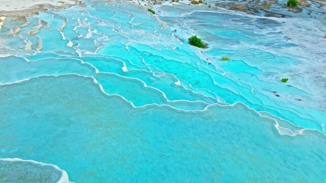 Aerial view of Travertines of Pamukkale, Turkey. Turquoise thermal pool surrounded by white limestone creates a scenic natural landmark view.