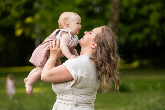 Mother lifting baby girl outdoors during summer family time