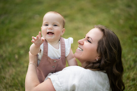 Happy mother holding baby girl outdoors in summer time