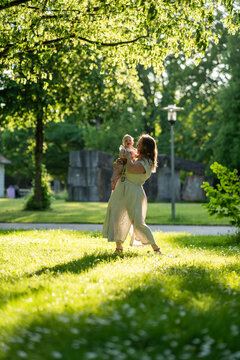 Mother holding baby girl in sunny park, summer family time