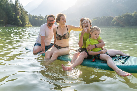 Family relaxing on paddleboard at a mountain lake in summer