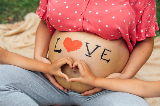 Pregnant mother belly with LOVE sign and family hands