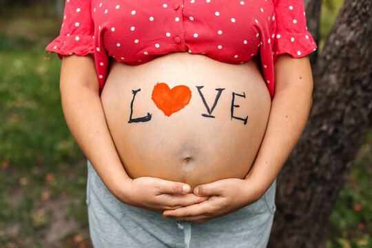 Pregnant belly with LOVE message painted outdoors
