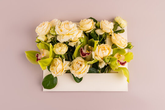 Cream roses and orchid bouquet in white envelope on pink