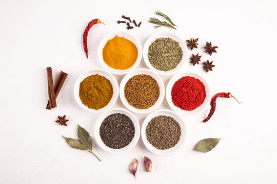 Assorted spices and seeds in bowls on white background