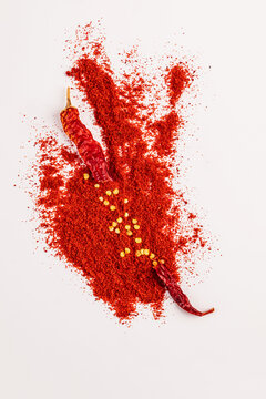 Red chili pepper with paprika powder splash on white
