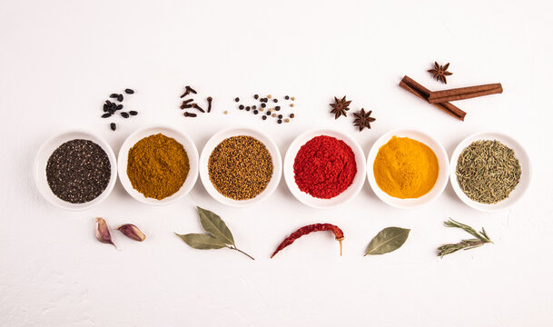 Colorful spice assortment in bowls on white background