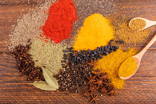 Assorted spices and seeds on rustic wooden table flat lay