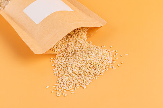 Flax seed spilling from paper pouch on pastel background