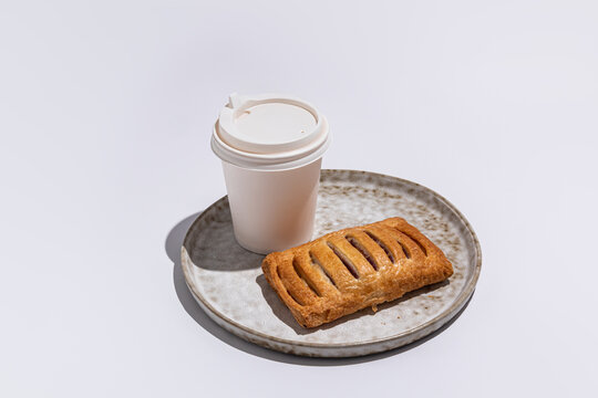 Takeaway coffee with fresh pastry on rustic plate
