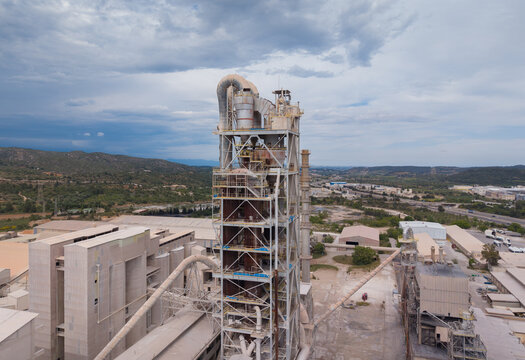 Multi-stage cyclone preheater tower with suspension preheater system, raw meal feed pipes, calciner vessel and steel access platforms at an industrial cement production facility