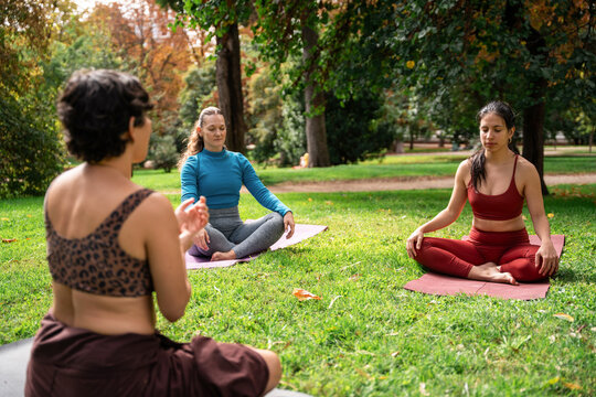 Multiethnic women meditating together on yoga mats in park