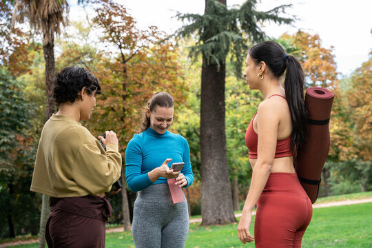 Multiethnic women in park checking phone before yoga