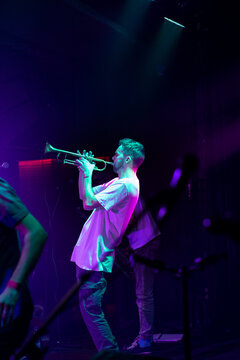 Trumpet player man performing on stage under neon concert lights