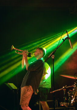 Trumpet player man performing on stage with green concert light